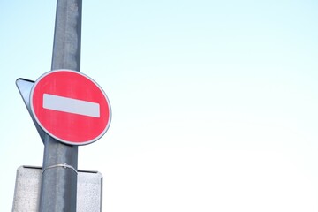 Red no-entry traffic sign on metal pole against clear sky. Do not enter round sign for cars,...