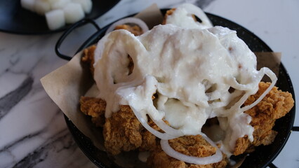 Creamy Onion Korean fried chicken on a black plate.