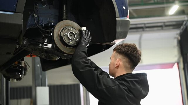 The master works with the brake system and suspension of the car at the service.