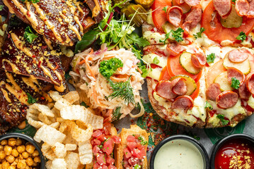 A vibrant food assortment featuring glazed ribs, cheesy pizza, fresh salad, crispy chips,...