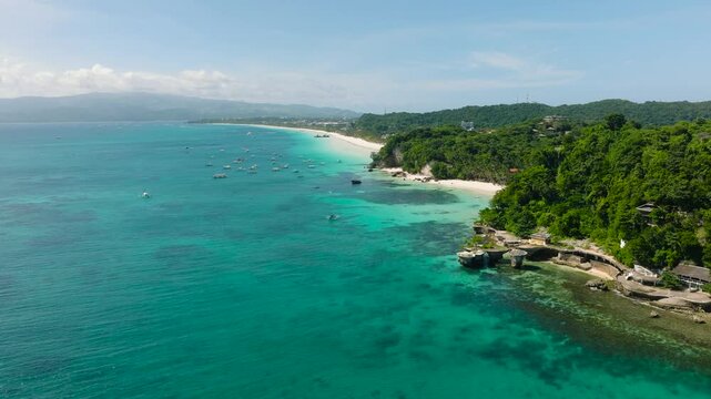 Coastline with vibrant turquoise water, lush green surroundings, and scattered traditional boats. Boracay Island, Philippines.