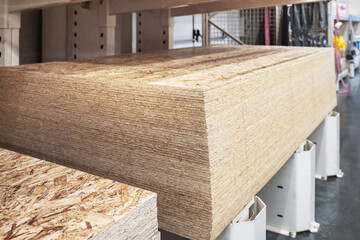 OSB boards and chipboard are neatly organized on pallets inside a building materials store, ready for customers.