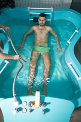 Therapeutic Water Bath.Man relaxing in hydrotherapy bath while therapist adjusts water settings.