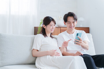 スマホを見る妊婦の妻と夫