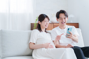 スマホを見る妊婦の妻と夫
