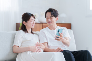 スマホを見る妊婦の妻と夫