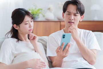 スマホを見る妊婦の妻と夫
