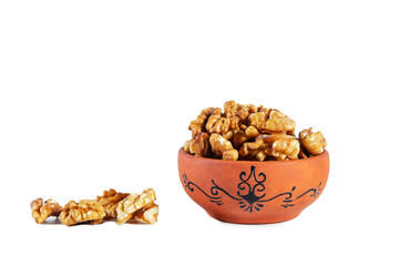 Heap of walnuts in clay bowl isolated on white background.