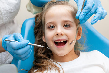 dentist, doctor examines the oral cavity of a little girl, uses a mouth mirror, baby teeth...