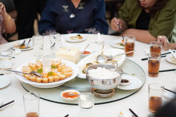 A serving of heavy Chinese food in the form of roulade and rice and other side dishes with a glass...