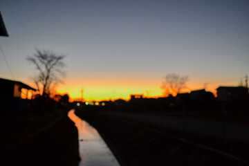 Fototapeta premium Abstract Blurry Orange Sunset Reflecting on a Wet Surface with Dark Silhouettes