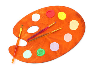 Wooden palette with paints and brushes isolated on white, top view