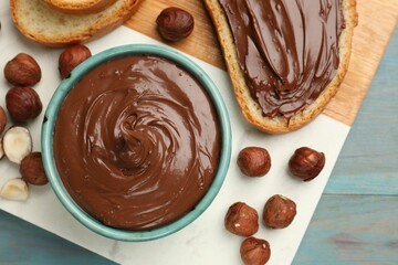 Toast with tasty chocolate hazelnut spread and nuts on blue wooden table, top view