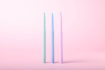 Colorful twist up eye pencils on pink background, closeup