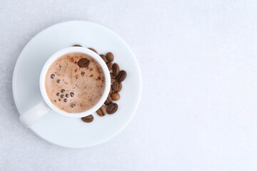Aromatic coffee in cup, beans and saucer on light table, top view. Space for text