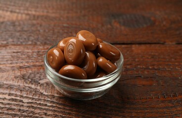 Many tasty caramel candies on wooden table, closeup