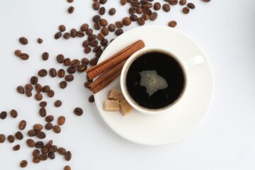 Aromatic coffee in cup, beans, cinnamon and sugar cubes isolated on white, top view