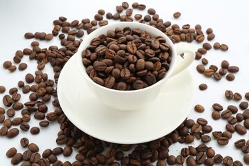 Aromatic coffee beans and cup on white background, closeup