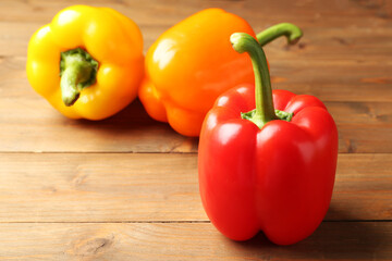 Ripe colorful bell peppers on wooden table, closeup