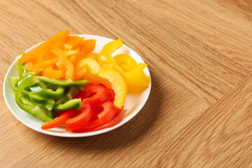 Slices of fresh colorful bell peppers on wooden table, closeup. Space for text