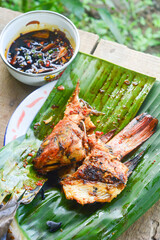 Close up of grilled fish cooked with tomatoes and spicy red chilies