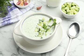 Tasty cucumber soup with dill and microgreens served on white marble table, closeup