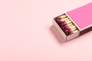 Matches in box on pink background, closeup. Space for text