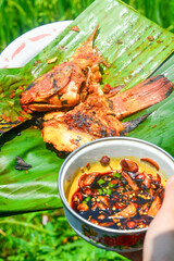Close up of grilled fish cooked with tomatoes and spicy red chilies