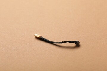 One burnt match on beige background, closeup