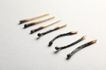 Burnt matches on light grey background, closeup
