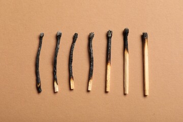 Burnt matches on beige background, flat lay