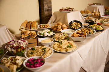 Buffet feast featuring an array of diverse dishes set up for an event in a cozy indoor venue during evening hours