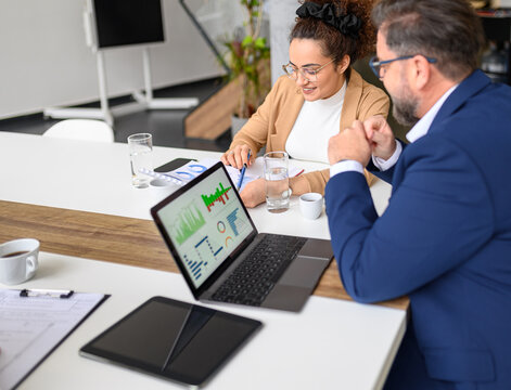 High angle view of businessman analyzing financial report with female colleague over laptop and documents in meeting