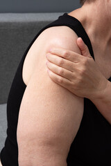 Adult woman with pain in arm holding herself. Self-care, preventive medicine