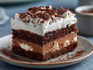 A decadent slice of chocolate cake with layers of creamy filling and whipped topping, sprinkled with chocolate.