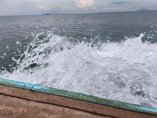 waves crashing on the rocks Water splashed up the side of the ship that was sailing in the sea in various white foam waves.