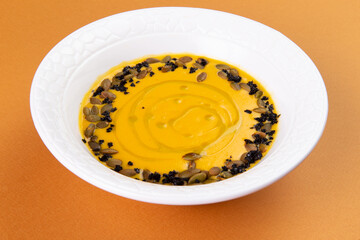 Pumpkin soup garnished with seeds in a plate.