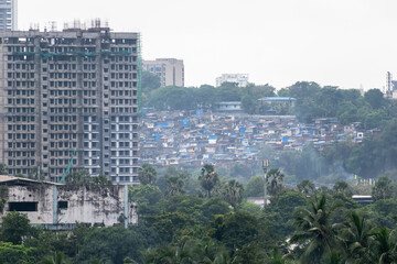 In Mumbai, a modern high-rise building overlooks a sprawling slum area, highlighting the stark contrast between wealth and poverty.