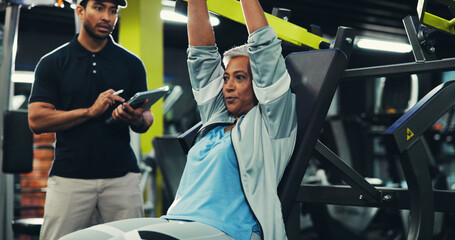 Personal trainer, senior woman and machine at gym for chest press, muscle strength and wellness. Retirement fitness, instructor and tablet for workout progress, exercise monitor and training support