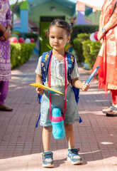 indian kid cute expression with beg and water bottle for first day of school at sunny day