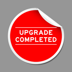 Red color peel sticker label with word upgrade completed on gray background