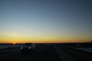 Fototapeta premium Sunset Highway Drive with Cars on the Road and Snow Lined Landscape