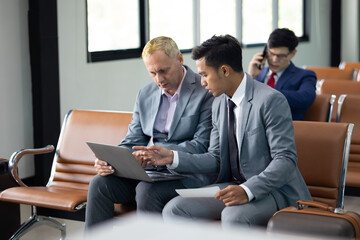 Fototapeta premium Business trip vacation and travel concept. caucasian and Asian business Man travelling by plane and working on laptop computer