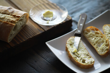 Freshly Sliced Baguette with Butter on Rustic Wooden Table for Breakfast or Snack