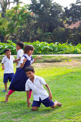 Children in school uniforms play freely on a sunny field, laughing and moving with energy and joy