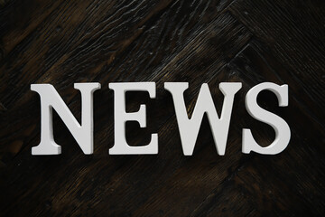 White NEWS Typography on Dark Wooden Background