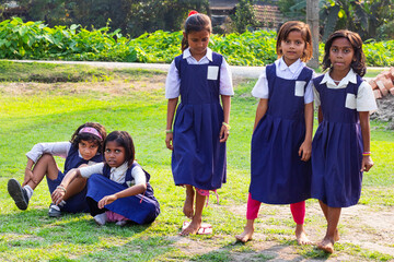 A group of schoolgirls in uniform gather on a grassy field�some standing confidently while others sit closely together