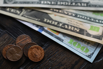 Close-Up of US Currency: Dollar Banknotes and Pennies Spread on a Dark Wooden Surface