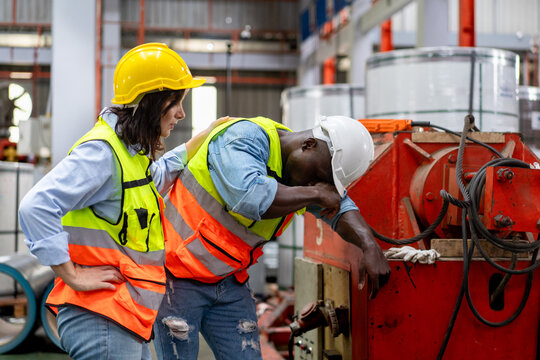 tired male worker feeling sick after stressed work in manufacturing factory, exhausted man technician has problem working overload, female foreman support consoling and encorage at industrial plant