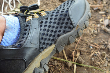 Mood photo of male legs wearing sportive hiking shoes with strong protective sole. Mens legs in trekking footwear for mountain travel standing on stone outdoor at nature on abstract background.